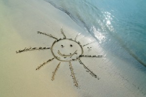 Lachende Sonne in den Sand des Strandes gezeichnet